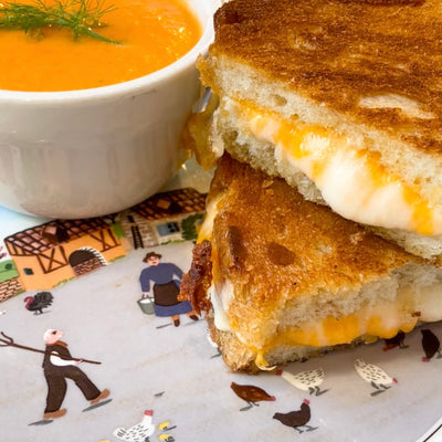 Image of a grilled cheese sandwich and a small bowl of tomato soup on a plate