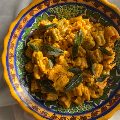 A plate of orange colored pasta with a pumpkin butter sauce