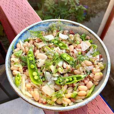 Bowl of salad with beans, peas, herbs and pancetta.
