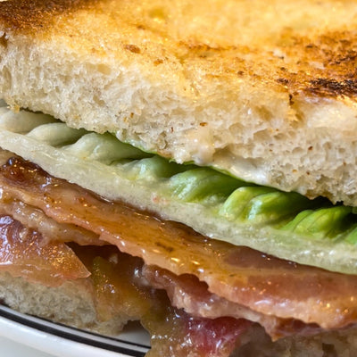 A close up of a spicy bacon lettuce and tomato sandwich